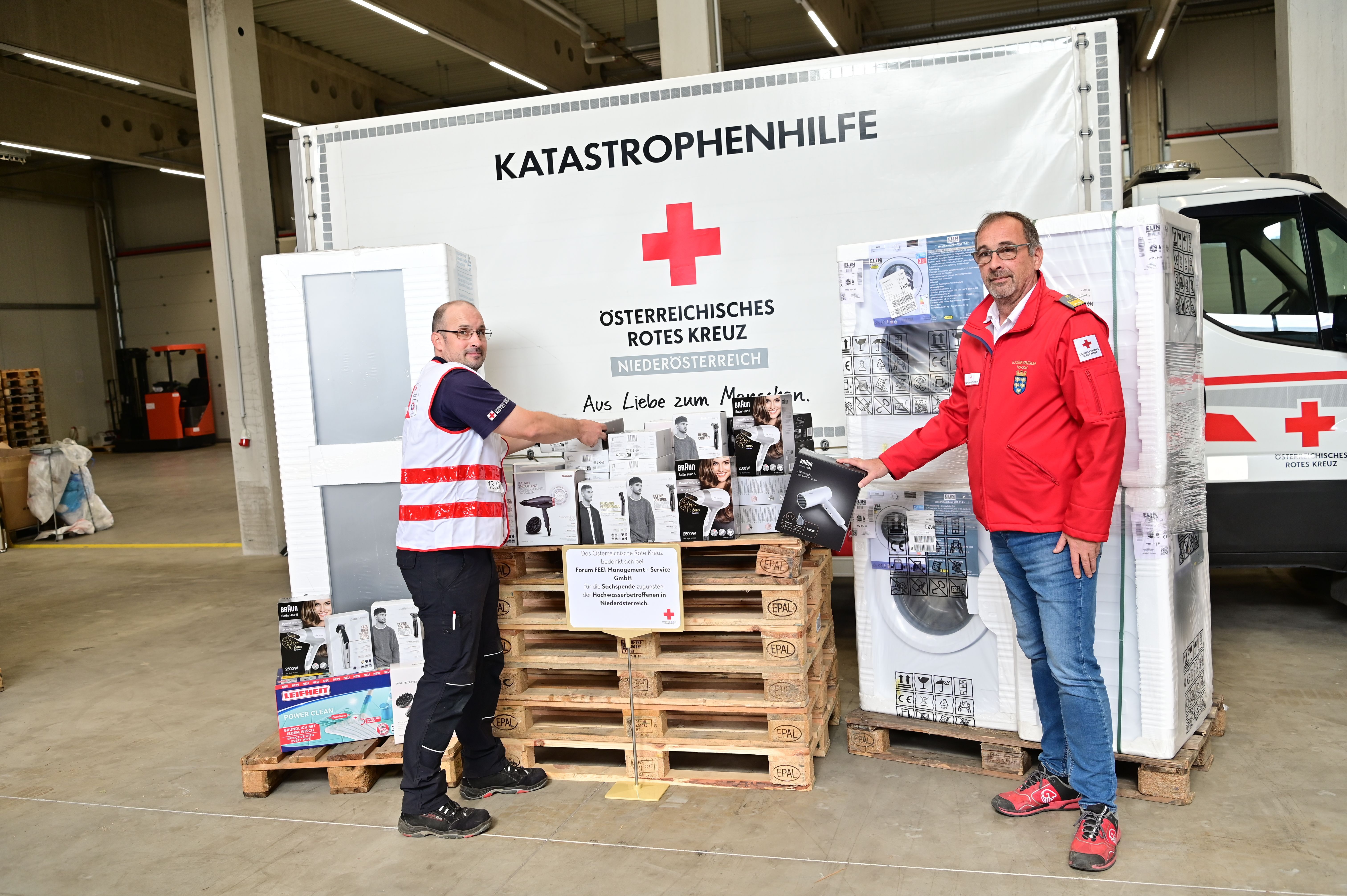 Bild: Zwei Personen stehen vor einer Garage. An der Wand hinter ihnen steht Österreichisches Rotes Kreuz